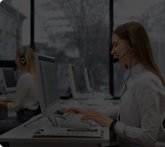 Customer care representative with a headset working at a computer
