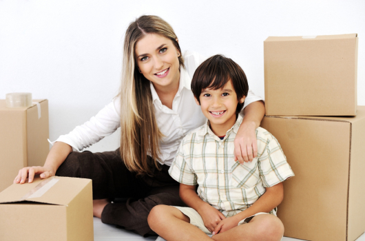Smiling mother and son sitting among moving boxes
