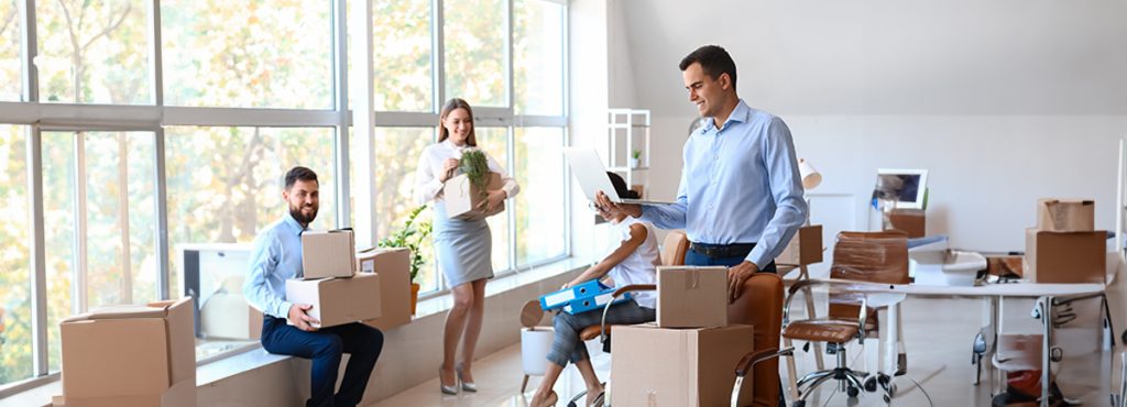Coworkers moving boxes in a bright office