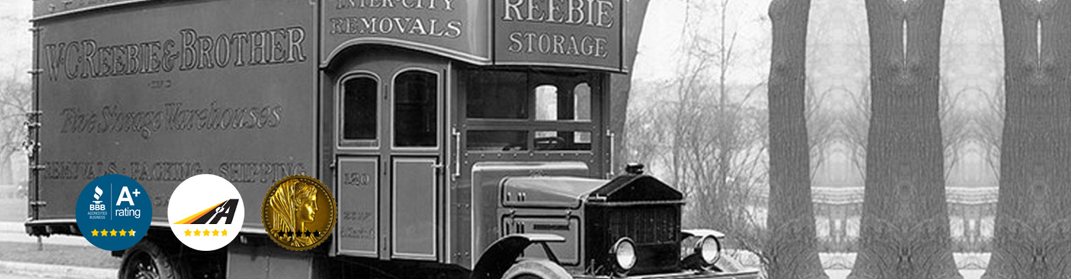 Black and white photo of a vintage Reebie Storage truck with award badges