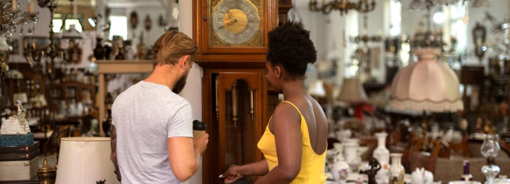 Couple looking at a grandfather clock in an antique shop