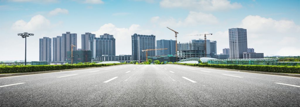 Empty highway leading toward a city skyline