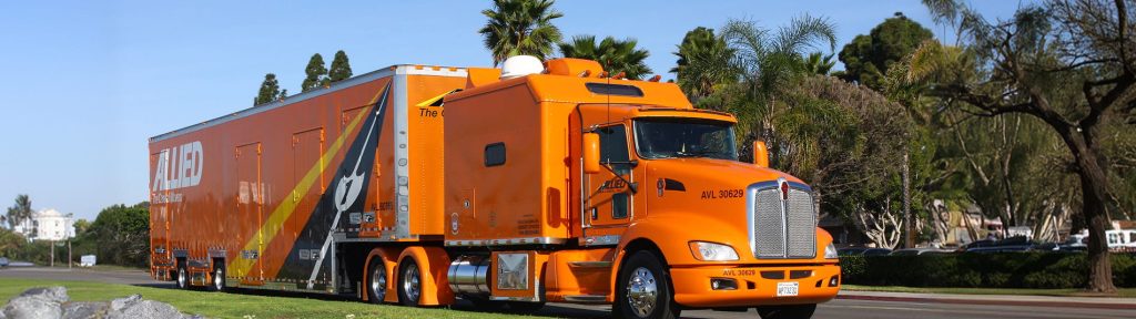 Orange Allied moving truck driving past houses and palm trees